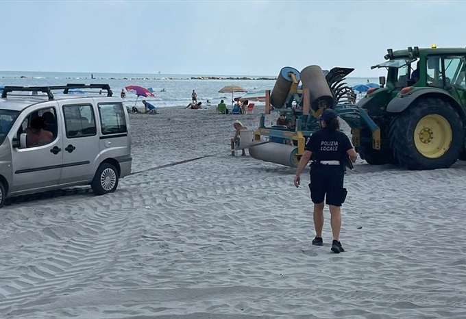 Parcheggia in spiaggia sotto l’ombrellone, auto portata via col trattore