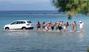 SUV finisce in mare e i bagnanti formano una catena umana per tirarlo fuori dall’acqua [VIDEO]