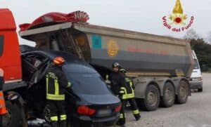 BMW prende un cordolo, vola e si incastra in un Tir: un ferito