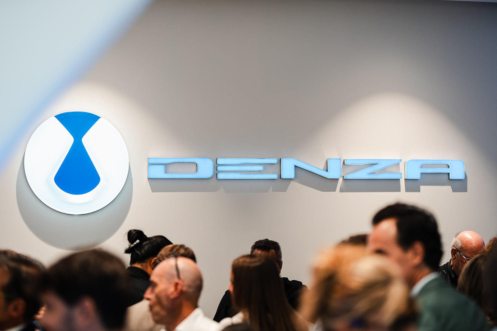 Il logo DENZA e il pubblico presente all'inaugurazione dello showroom di Torino